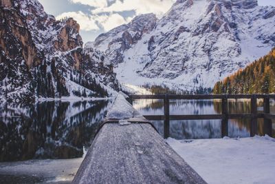 Frozen lake by snowcapped mountains against sky