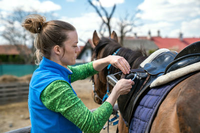 Side view of woman standing by horse