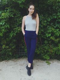 Full length of young woman standing against plants