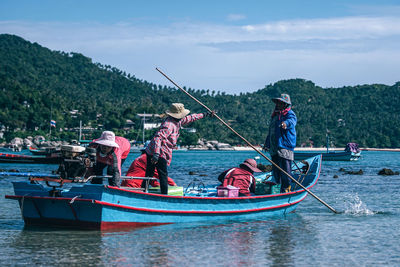 People fishing in sea against sky