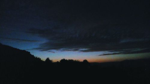 Silhouette of trees against cloudy sky