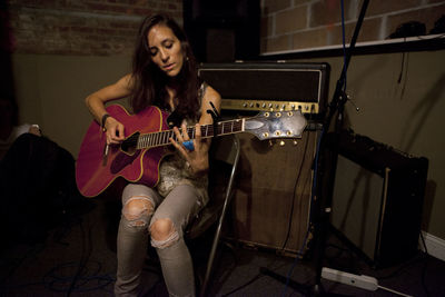 Young woman playing an acoustic guitar at band practice