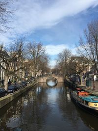 Canal amidst buildings in city against sky