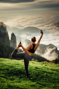 Rear view of woman exercising on mountain