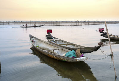 Boat moored in lake against sky during sunset