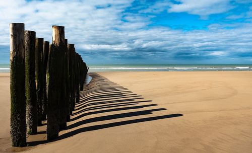 Wooden posts on beach against sky