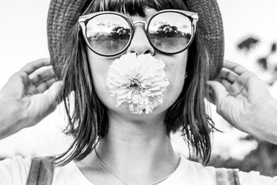 Close-up portrait of young woman carrying flower in mouth