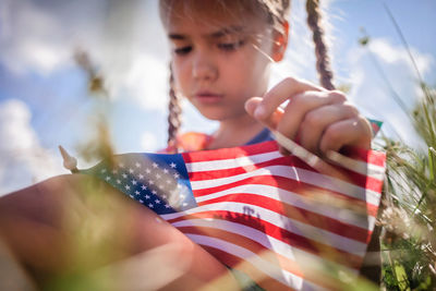 Patriot and national flag day celebration. little patriot sitting on the meadow and holding usa flag