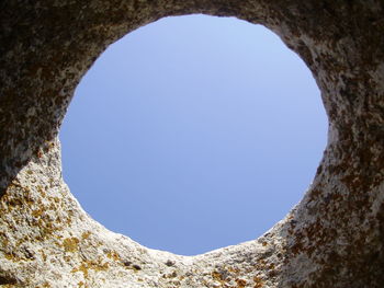 Low angle view of clear blue sky seen through hole