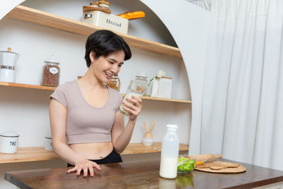 Portrait of young woman sitting on table at home