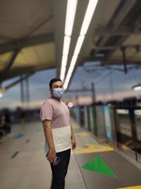 Portrait of young man standing at railroad station