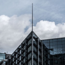 Low angle view of office building against cloudy sky