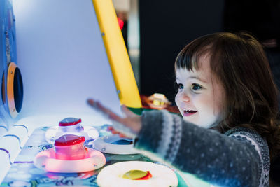 Close-up of girl playing with illuminated game