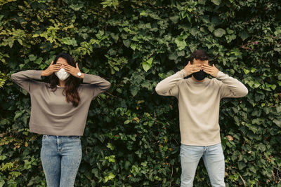 Midsection of man and woman standing against plants