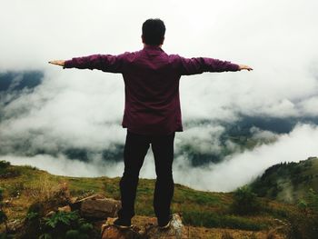 Rear view of man standing on landscape against sky