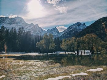 Scenic view of lake by snowcapped mountains against sky