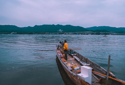 People on boat in sea against sky