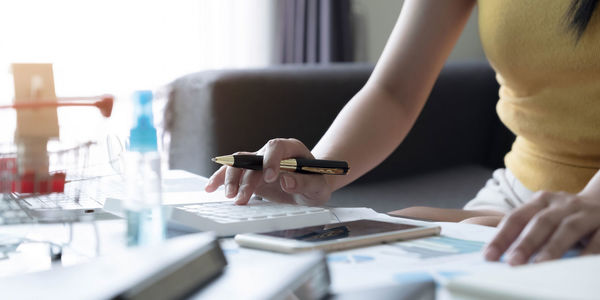 Midsection of woman holding umbrella on table