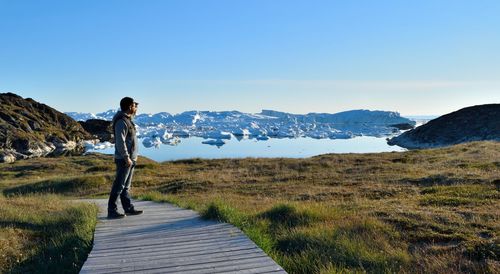 Man standing on boardwalk at ilulissat