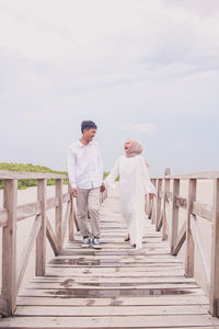 Couple standing on staircase against sky