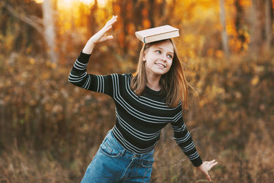 Portrait of smiling young woman standing by tree during autumn