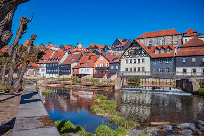 Reflection of houses and buildings in river against blue sky