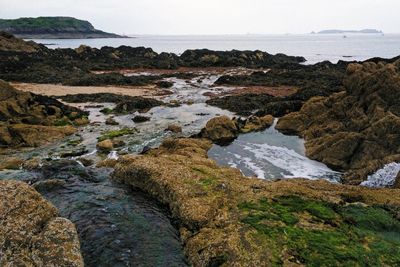 Rocks on sea shore against sky