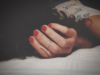 Woman with red nail polish lying on bed