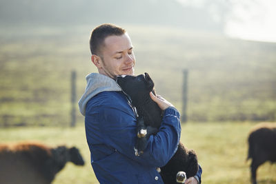 Man holding lamb in herd of sheep. portrait of farmer in organic farm in countryside. 