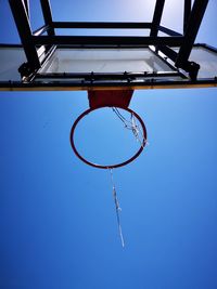 Low angle view of basketball hoop against clear blue sky during sunny day