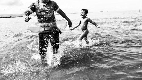 Midsection of man playing with little boy on sea shore