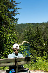 Man sitting on street amidst trees against sky