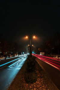 Light trails on road against sky at night