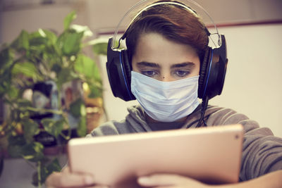 Boy wearing headphones while using digital tablet