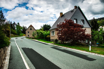 Road by buildings against sky