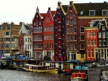 Buildings by canal against sky in city