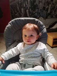 Portrait of cute baby girl sitting in stroller at home