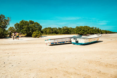 Tourists walking on the sandy beach next to fishing boats in mida creek in watamu in malindi, kenya