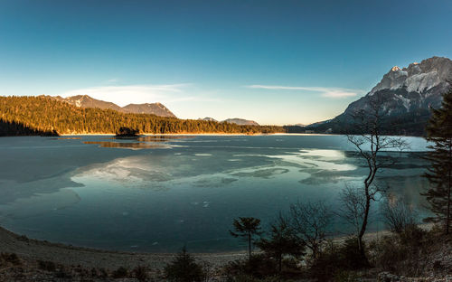 Scenic view of lake by mountains against blue sky