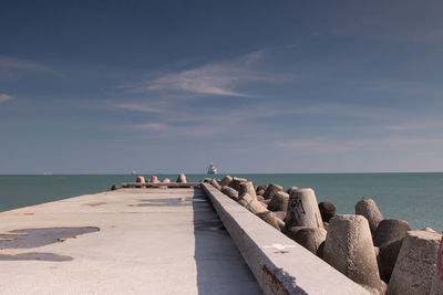 Pier by groynes against sea and sky