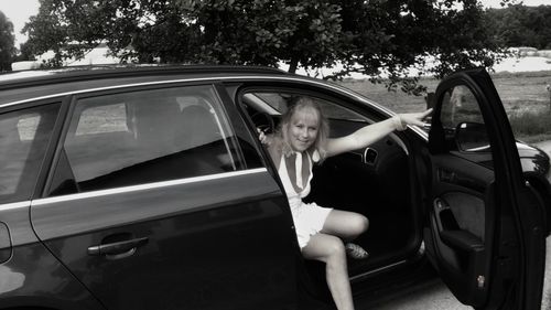 Portrait of woman getting out from black car