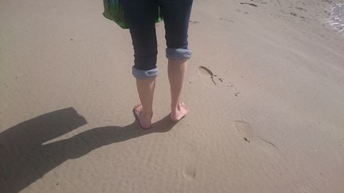 Low section of woman standing on sand at beach