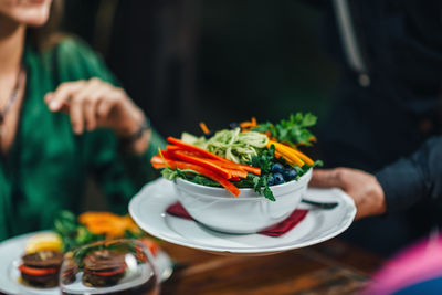 Cropped hand of waiter keeping food on table in restaurant