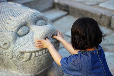 Rear view of girl touching sculpture