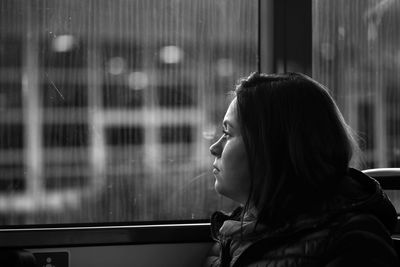 Side view of woman looking through bus window