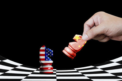 Low angle view of hand holding chess against black background