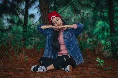 Full length of a young woman sitting in forest