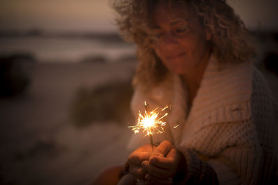 Woman holding sparkler at night
