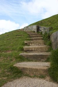 Low angle view of steps amidst grass against sky