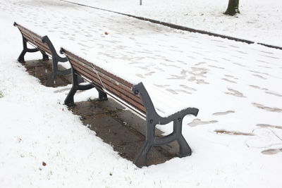 High angle view of empty bench on snow covered field